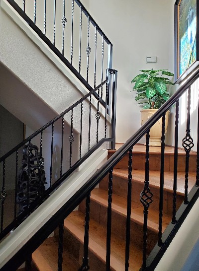 Close-up view of an interior staircase featuring intricate wrought iron hand railings, showcasing elegant scrollwork and detailed craftsmanship, adding a touch of classic sophistication to the space.