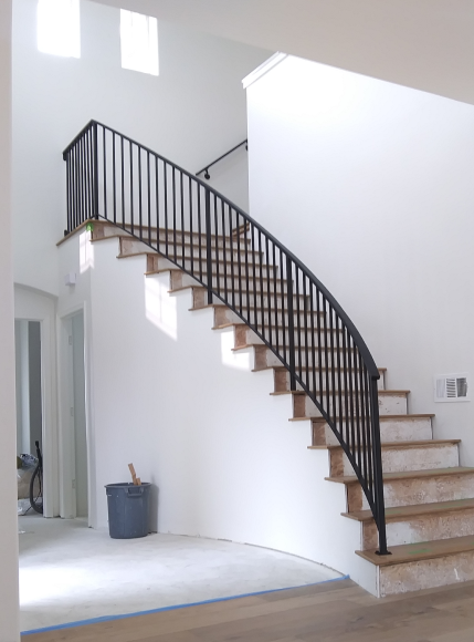 Interior shot of a curved staircase with a sleek, modern black hand rail, offering a minimalist and contemporary design element that enhances the overall aesthetic of the space.