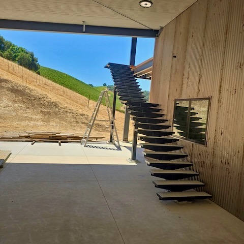 Completed custom metal staircase installed on the exterior of the building, featuring a sleek, modern design that complements the surrounding landscape.