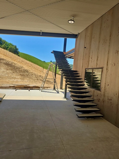 ompleted custom metal staircase installed on the exterior of the building, featuring a sleek, modern design that complements the surrounding landscape.