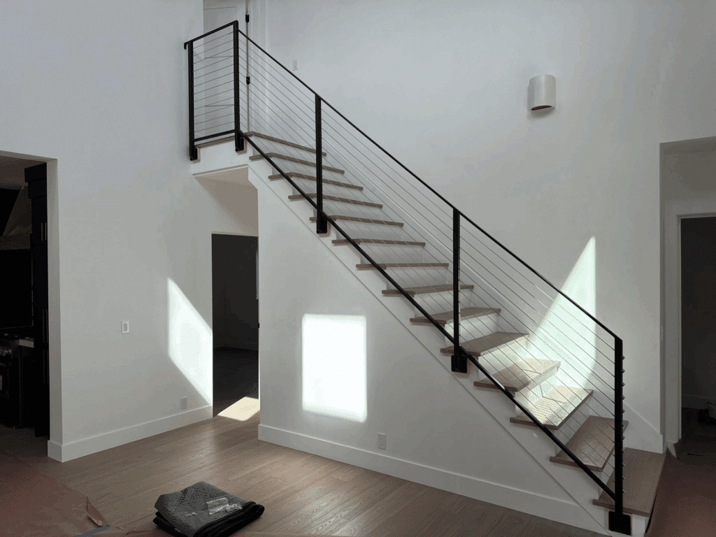 Sleek black metal and cable handrail system installed along modern staircase in Los Osos home