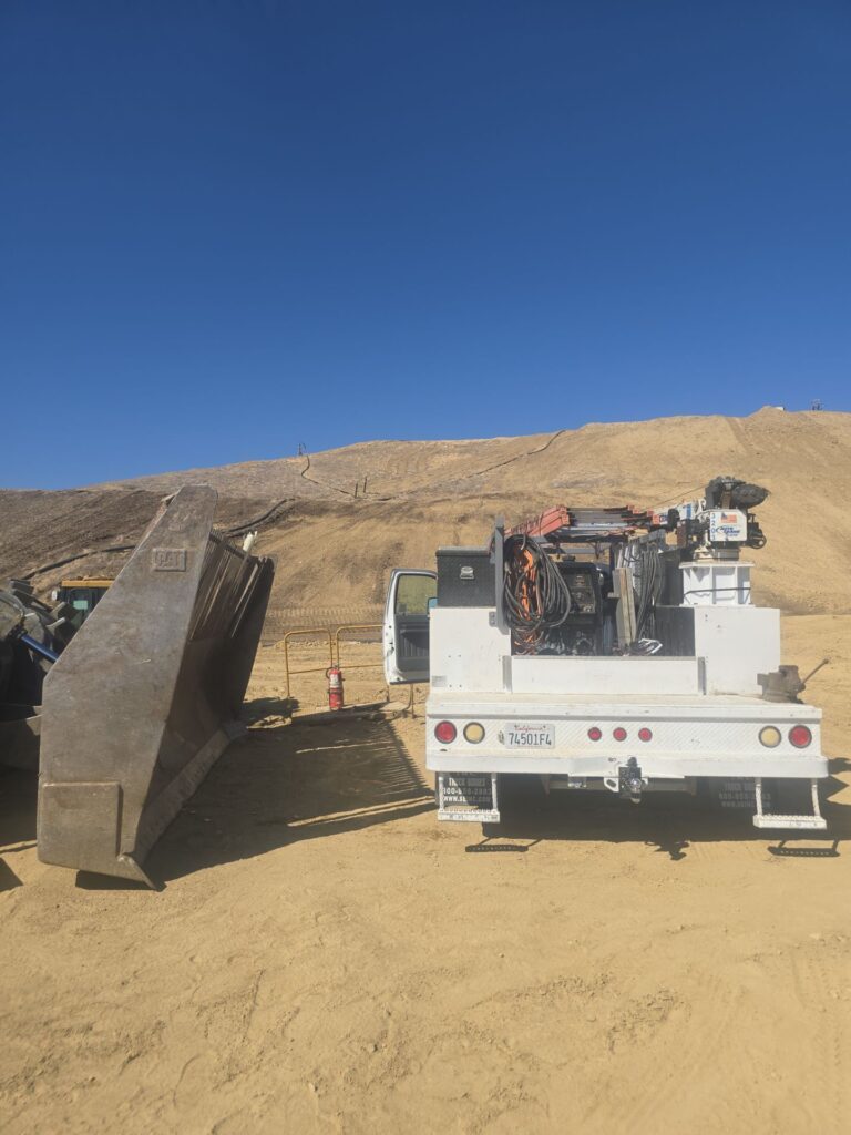 J&M Welding mobile service truck parked beside heavy equipment at waste management facility for on-site compactor repair