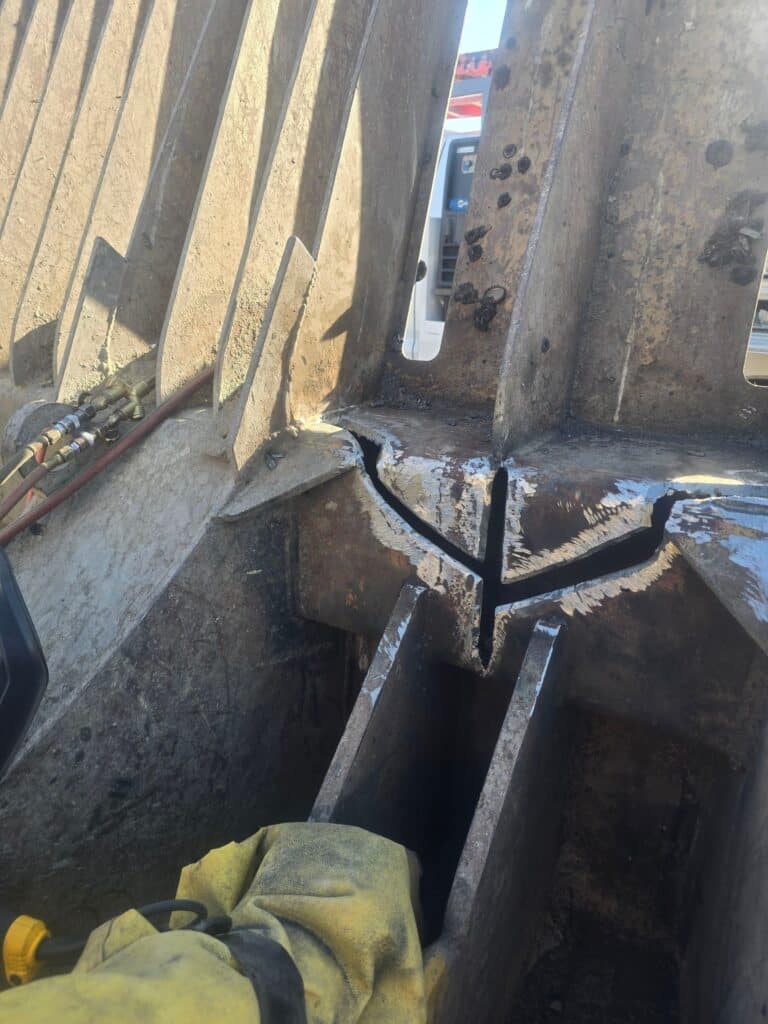 Ground-out crack on steel compactor part showing clean prepped metal ready for welding repair