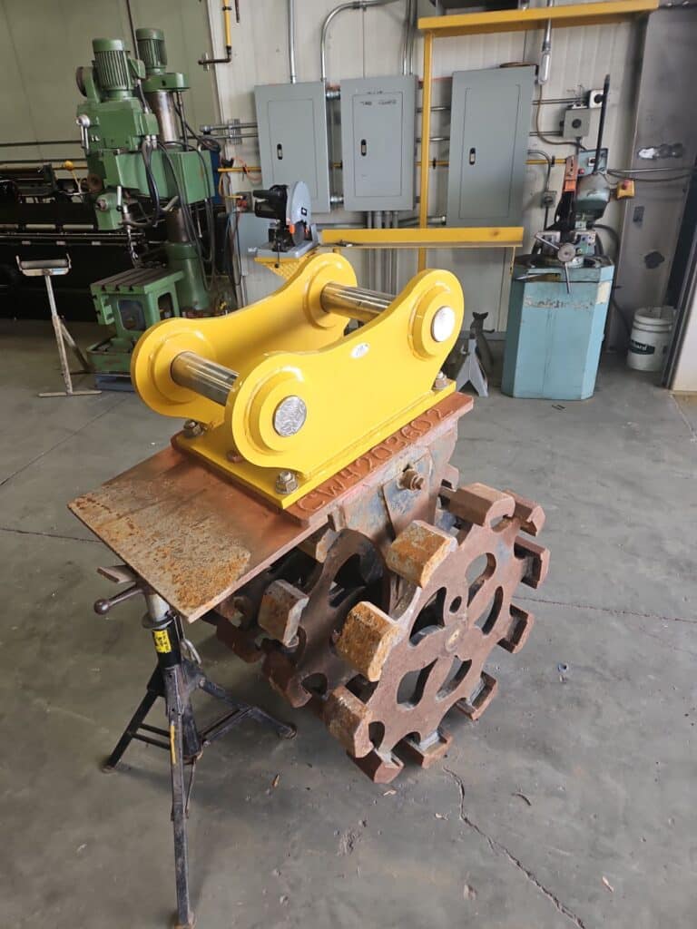 Finished excavator bucket ears painted and assembled with pins, ready for field use.