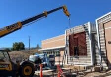 Crane setting a custom steel louver/screen panel into place on a commercial building exterior during installation.